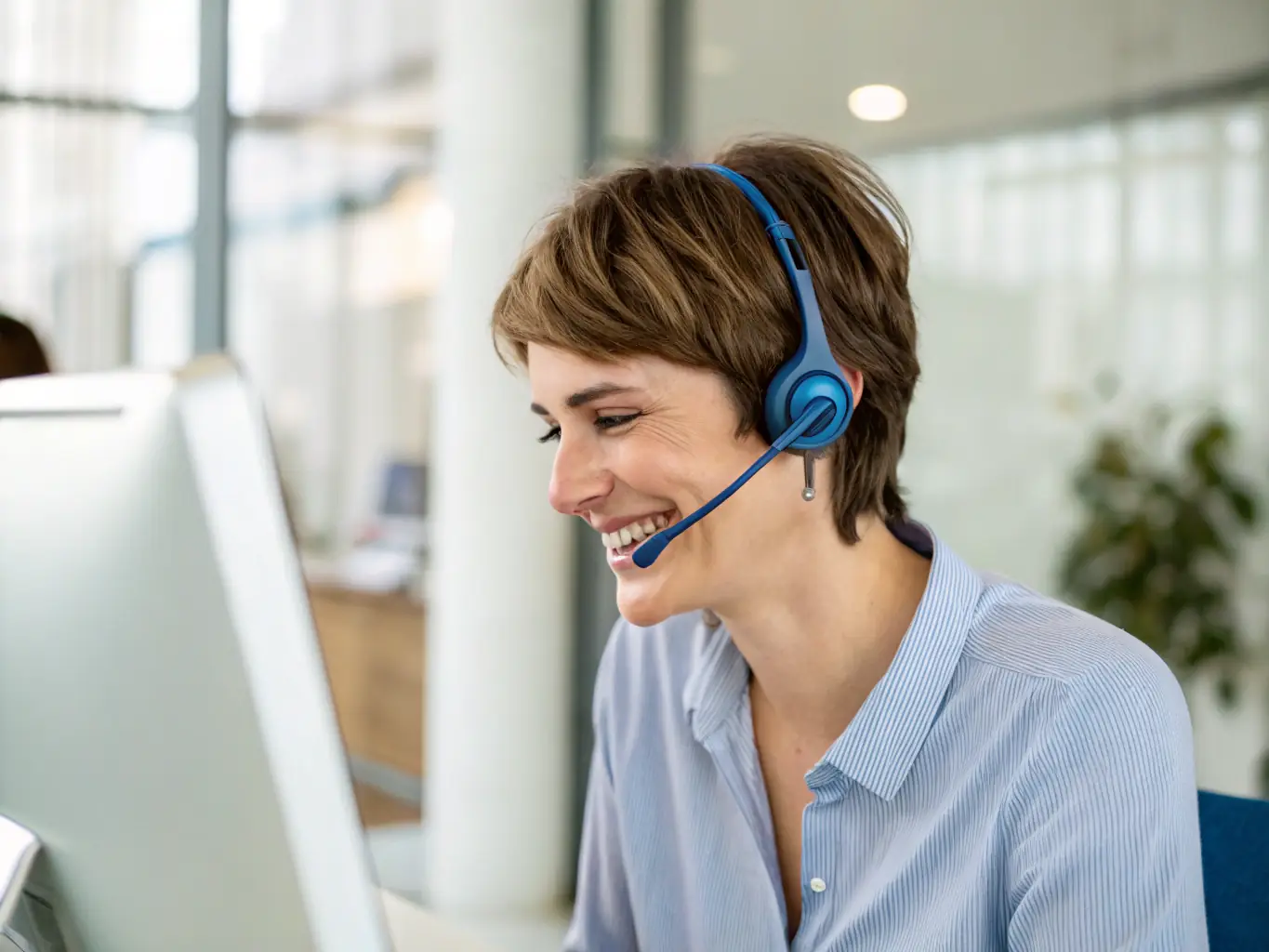 A friendly support agent with a headset, smiling and chatting on a laptop, with subtle geometric shapes and a sky-blue accent, conveying reliable customer support.